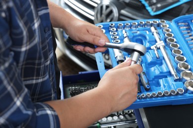 Auto mechanic with torque wrench at automobile repair shop, closeup