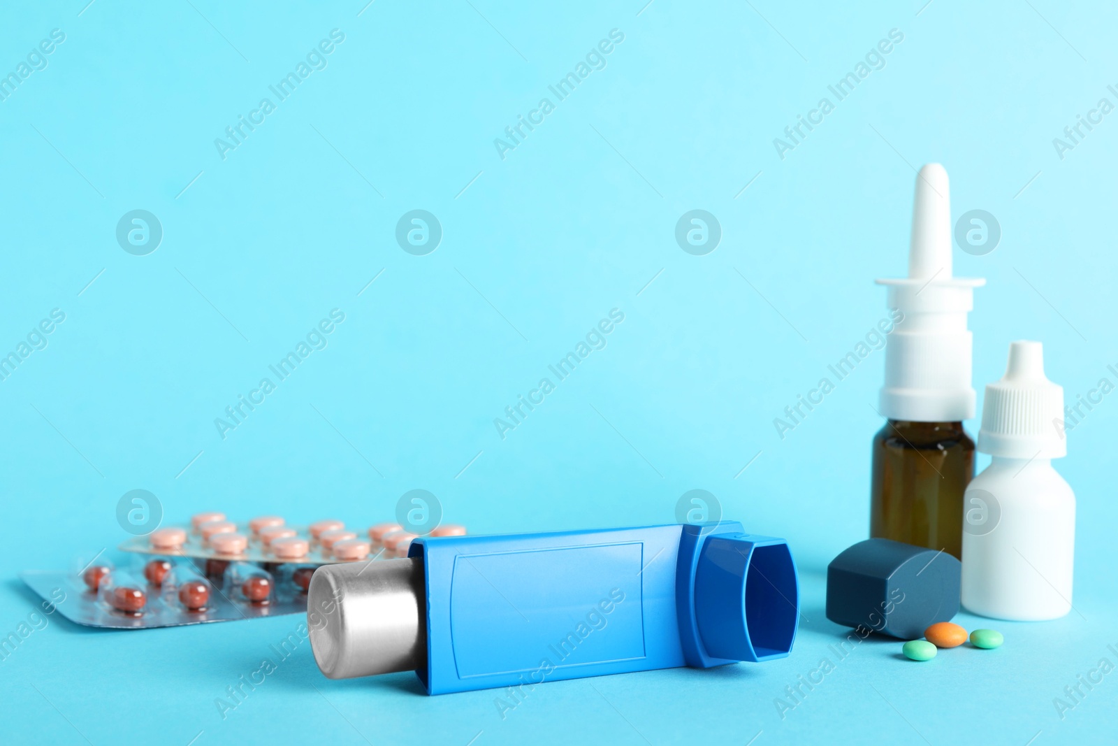 Photo of Different asthma medications on light blue background, closeup