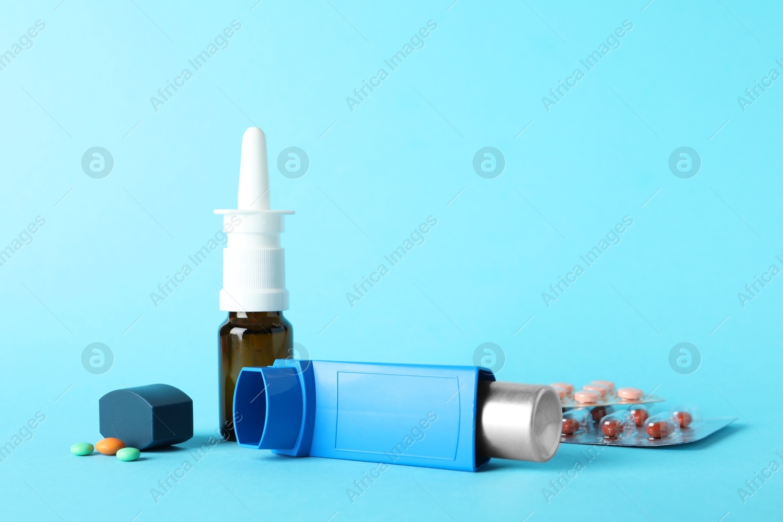 Photo of Different asthma medications on light blue background, closeup