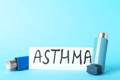 Photo of Card with word Asthma and inhalers on light blue background, closeup