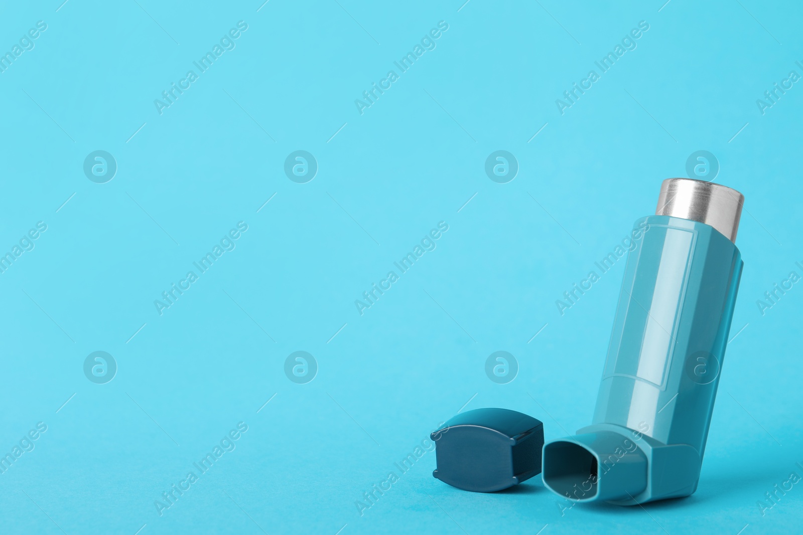 Photo of One inhaler on light blue background, closeup with space for text. Asthma treatment