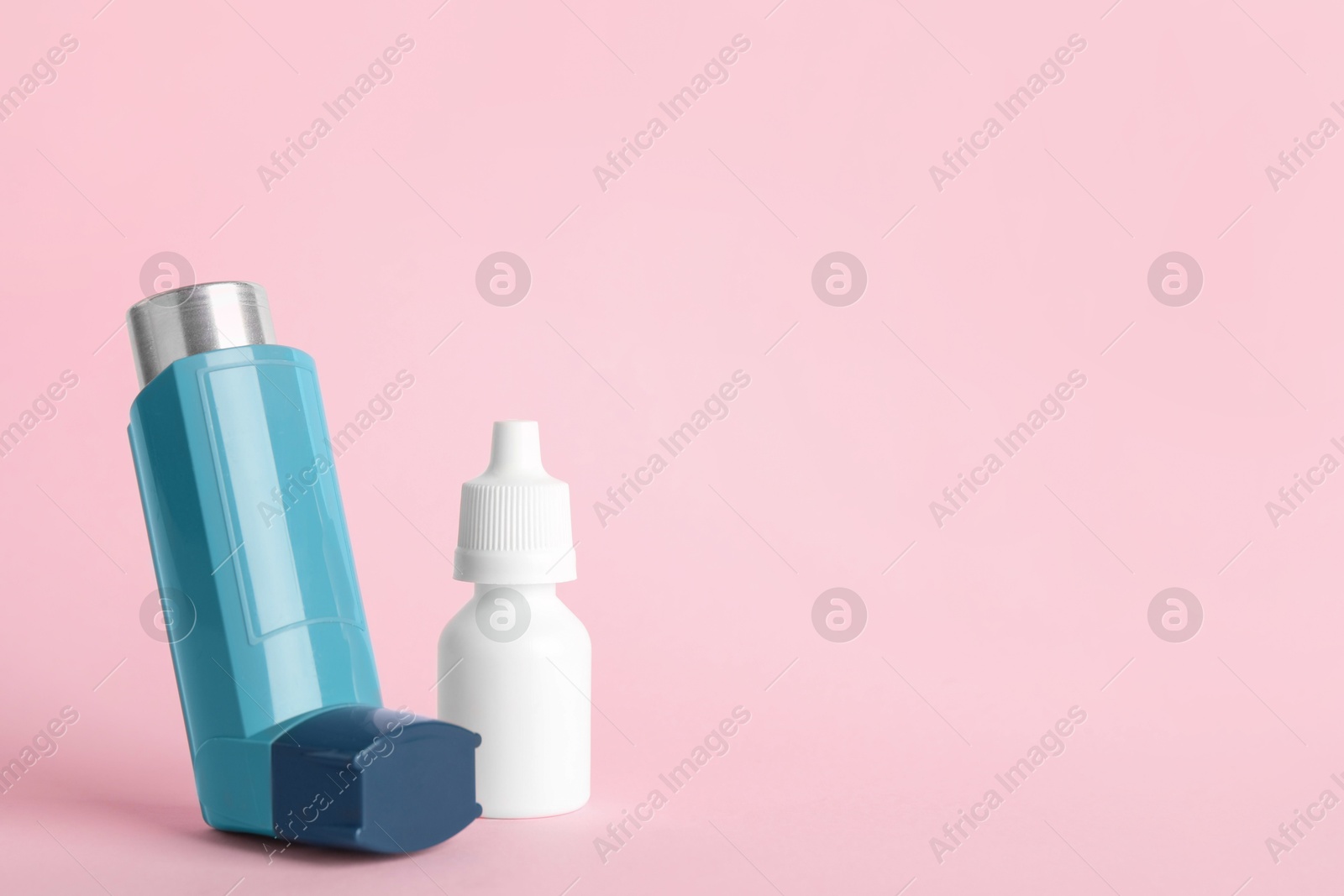 Photo of Asthma inhaler and medical drops on pink background, closeup. Space for text