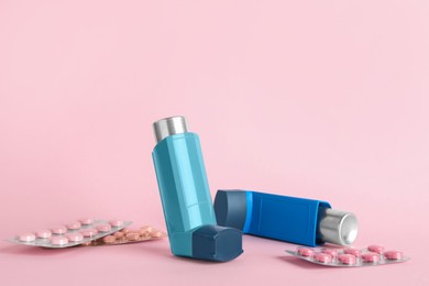 Photo of Inhalers and pills on pink background, closeup. Asthma treatment