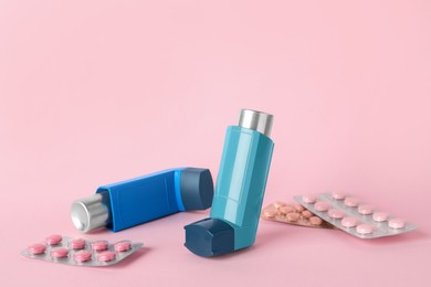 Photo of Inhalers and pills on pink background, closeup. Asthma treatment