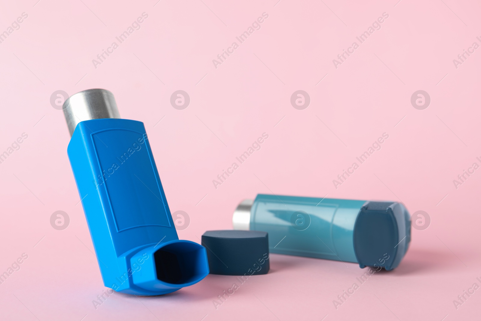 Photo of Inhalers on pink background, closeup. Asthma treatment