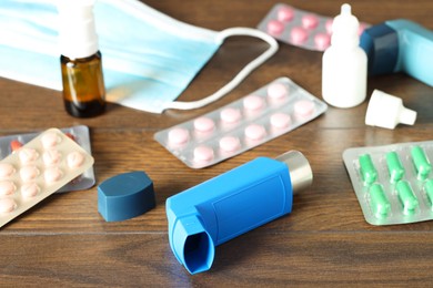 Photo of Different asthma medications on wooden table indoors, closeup