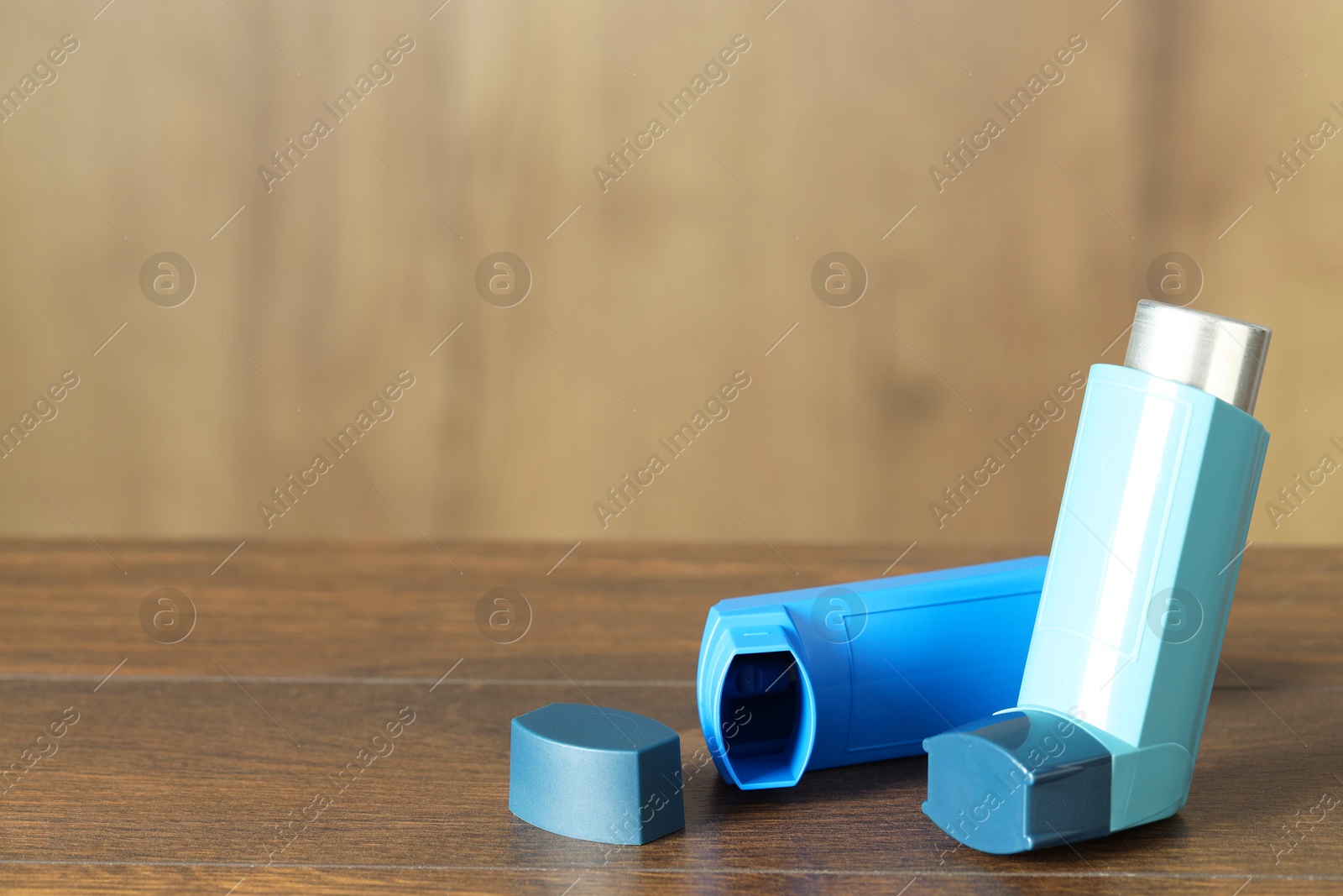 Photo of Inhalers on wooden table indoors, closeup with space for text. Asthma treatment