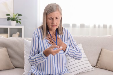 Photo of Senior woman suffering from heart pain pressing emergency call button at home