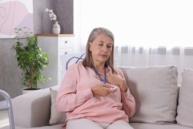 Senior woman suffering from heart pain pressing emergency call button at home