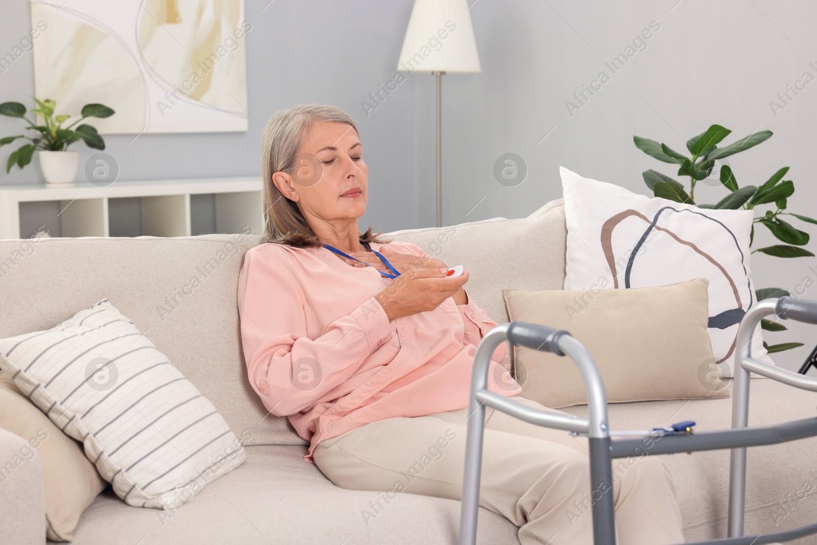 Photo of Senior woman suffering from heart pain pressing emergency call button at home