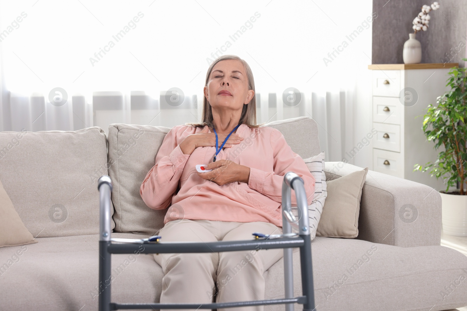 Photo of Senior woman suffering from heart pain pressing emergency call button at home