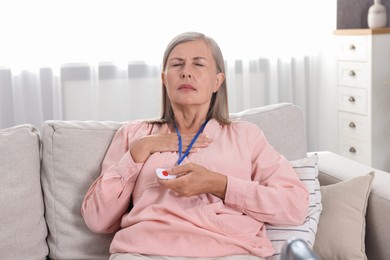 Senior woman suffering from heart pain pressing emergency call button at home