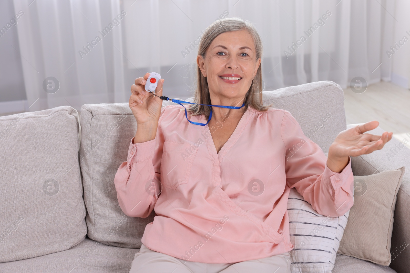 Photo of Happy senior woman with emergency call button at home