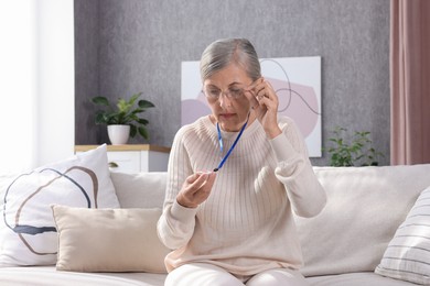 Senior woman in glasses with emergency call button at home