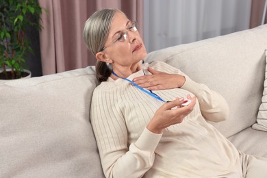 Senior woman suffering from heart pain pressing emergency call button at home