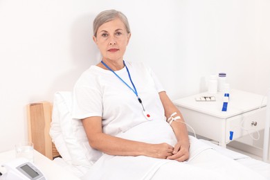 Senior woman with emergency call button on bed in hospital