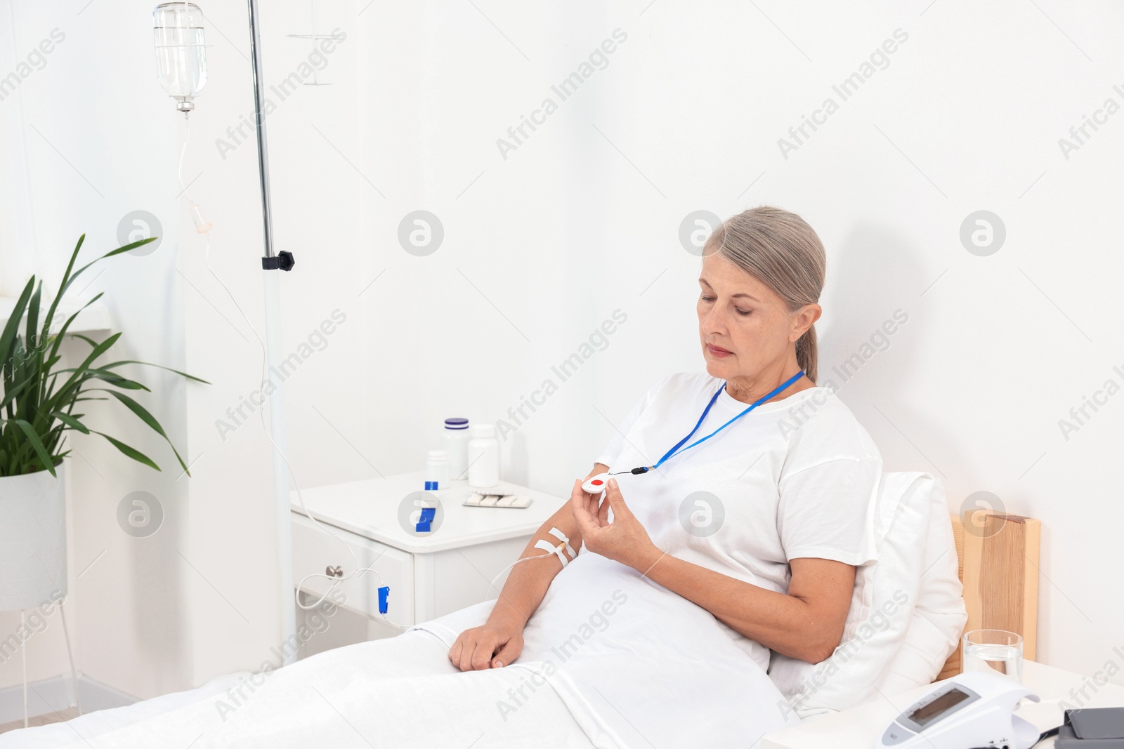 Photo of Senior woman with emergency call button on bed in hospital