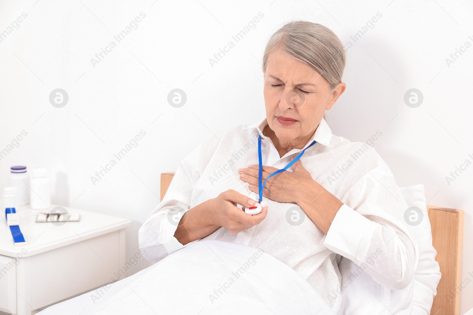 Photo of Senior woman suffering from heart pain pressing emergency call button on bed in hospital