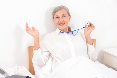 Happy senior woman with emergency call button in hospital