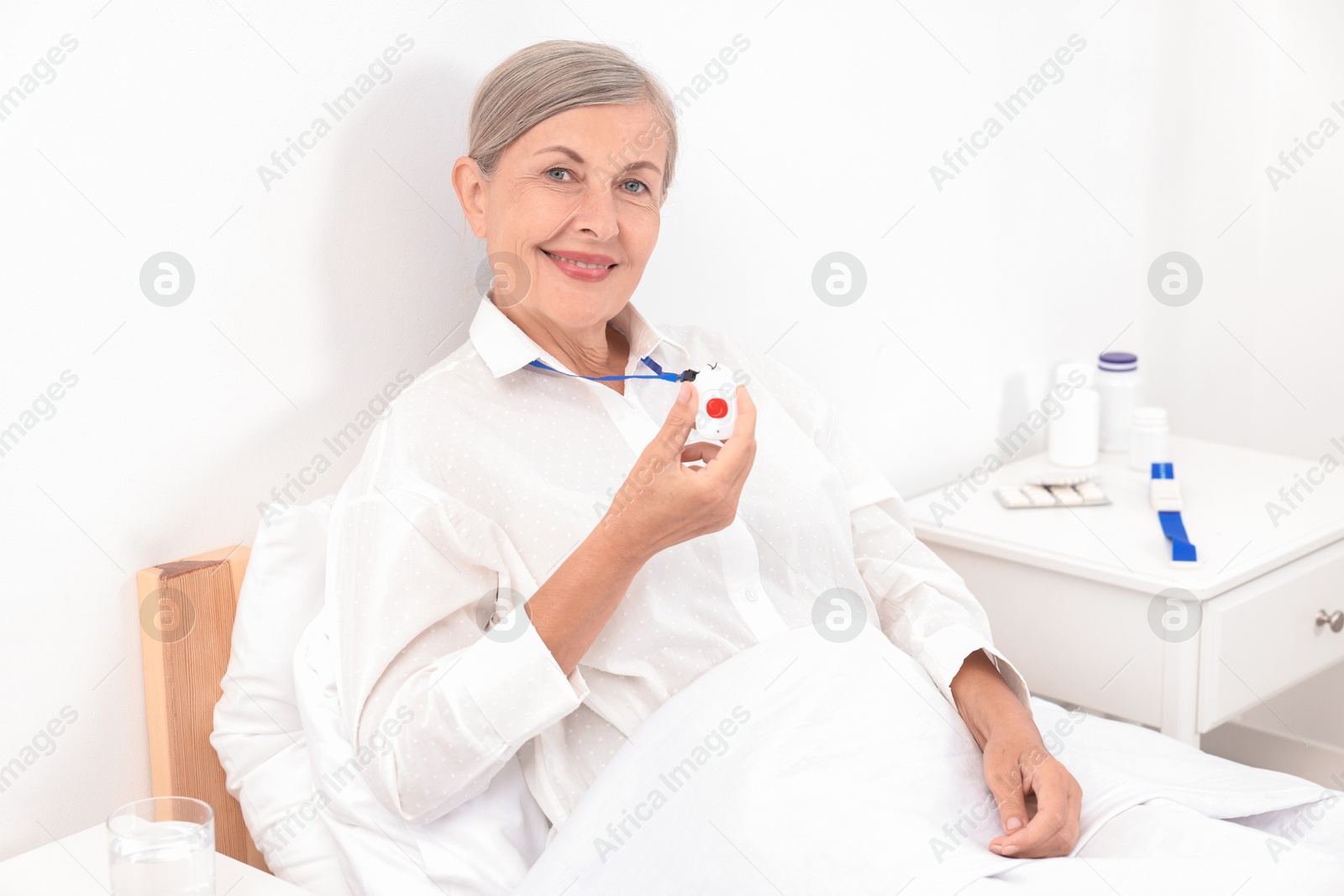 Photo of Happy senior woman with emergency call button in hospital