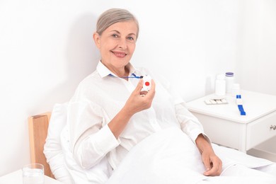 Happy senior woman with emergency call button in hospital