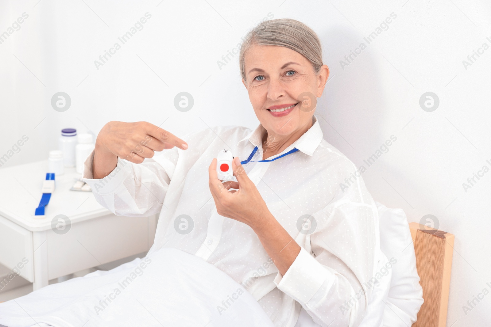 Photo of Happy senior woman pointing at emergency call button in hospital