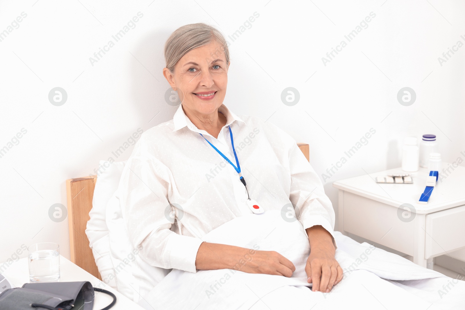 Photo of Happy senior woman with emergency call button in hospital