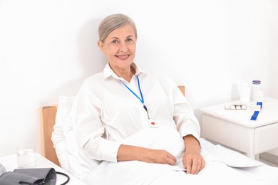 Happy senior woman with emergency call button in hospital