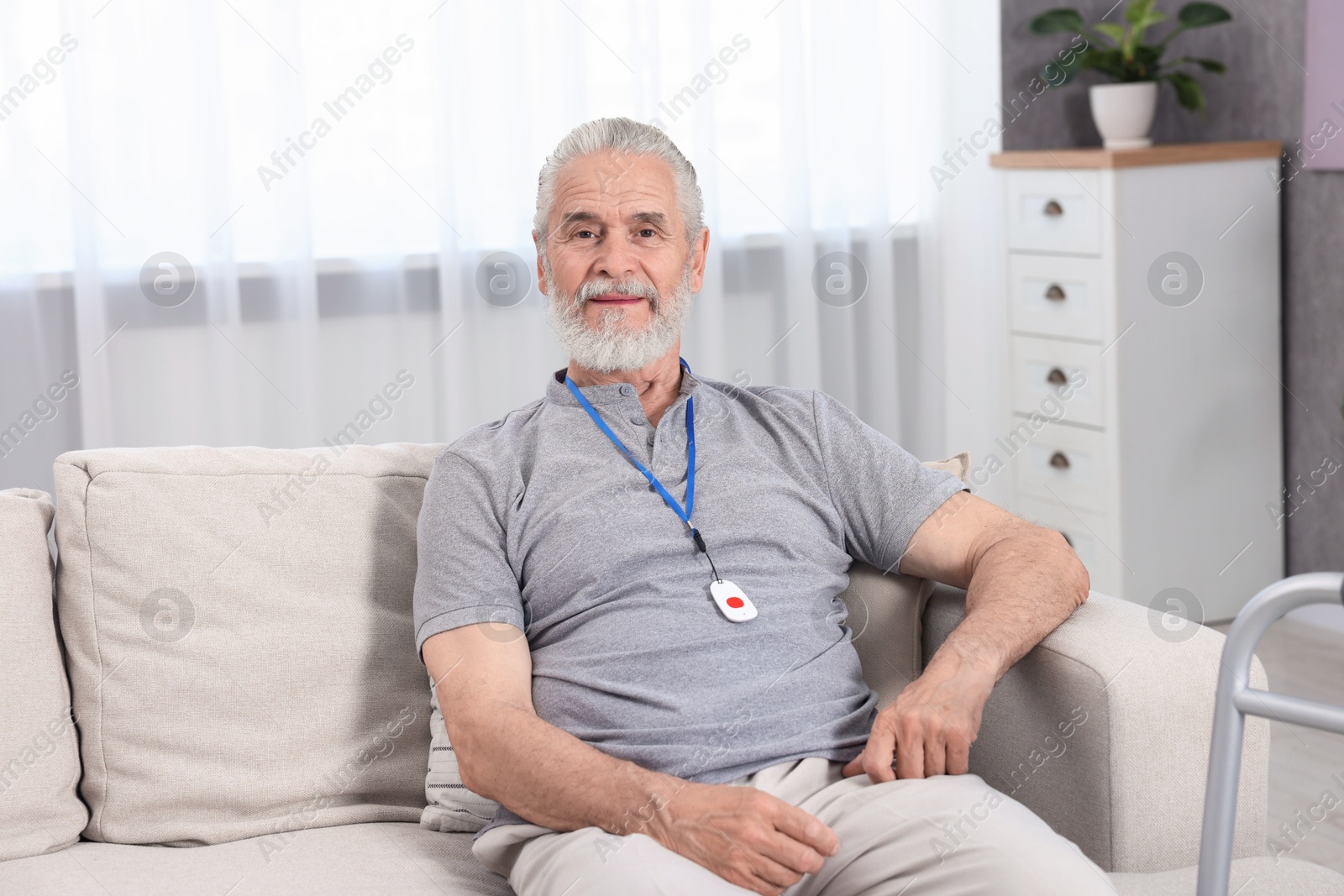 Photo of Senior man with emergency call button at home