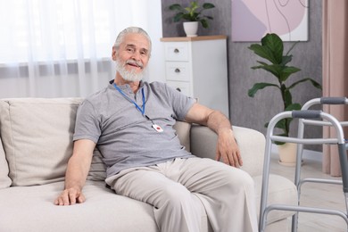 Happy senior man with emergency call button at home