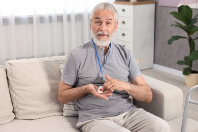 Senior man pressing emergency call button at home