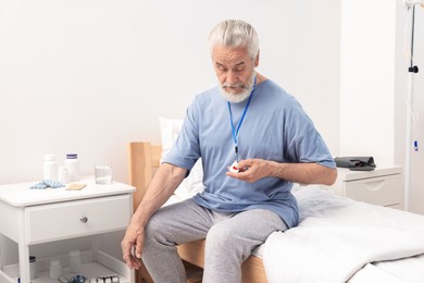 Senior man pressing emergency call button on bed in hospital