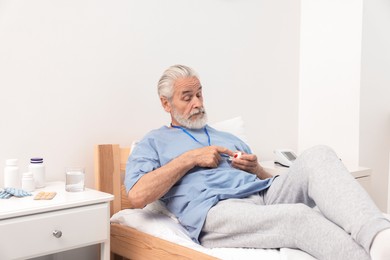 Senior man pressing emergency call button on bed in hospital