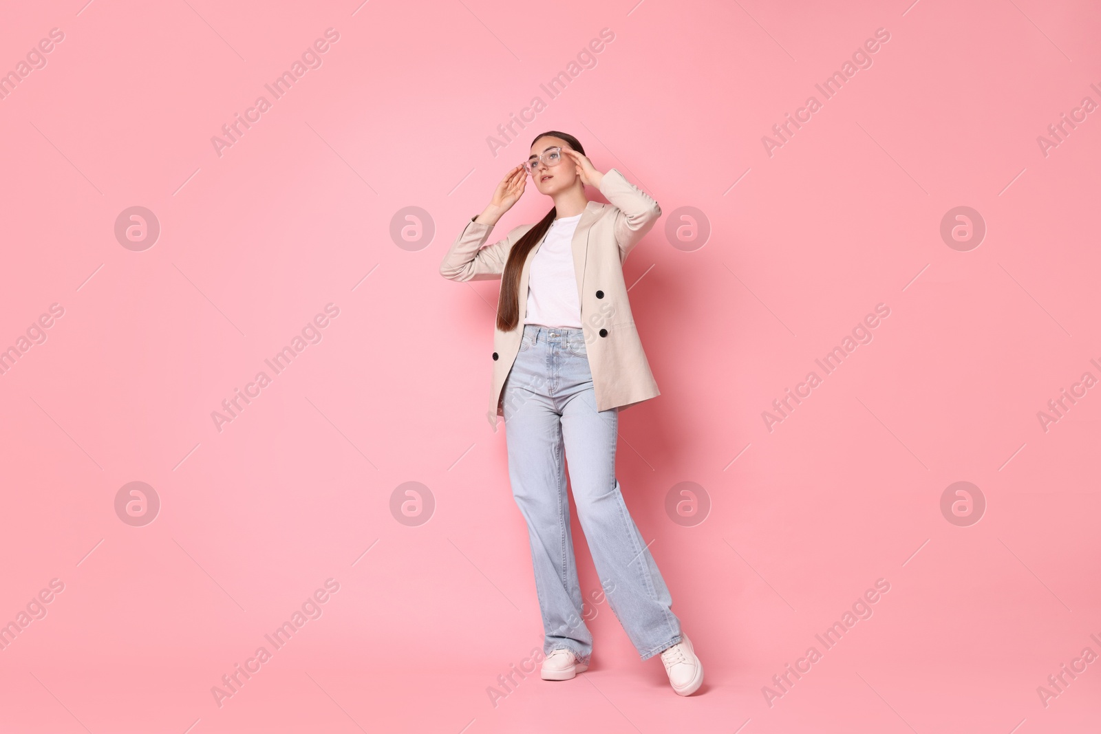 Photo of Stylish woman in beige jacket and jeans on pink background