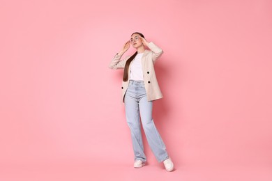 Photo of Stylish woman in beige jacket and jeans on pink background