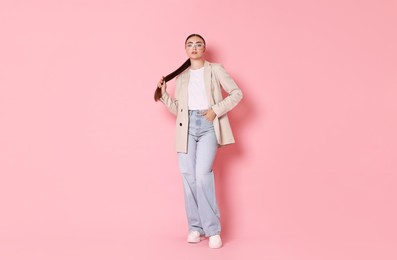 Stylish woman in beige jacket and jeans on pink background