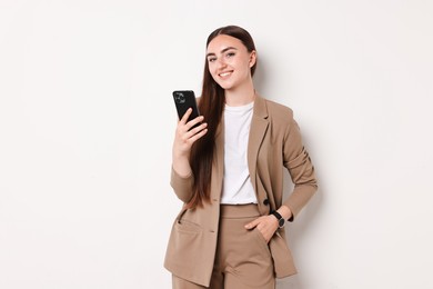 Photo of Woman in beige suit using smartphone on white background