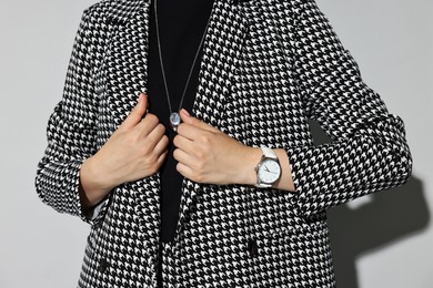 Woman in stylish suit on gray background, closeup