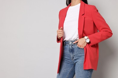 Woman in red jacket and jeans on gray background, closeup. Space for text