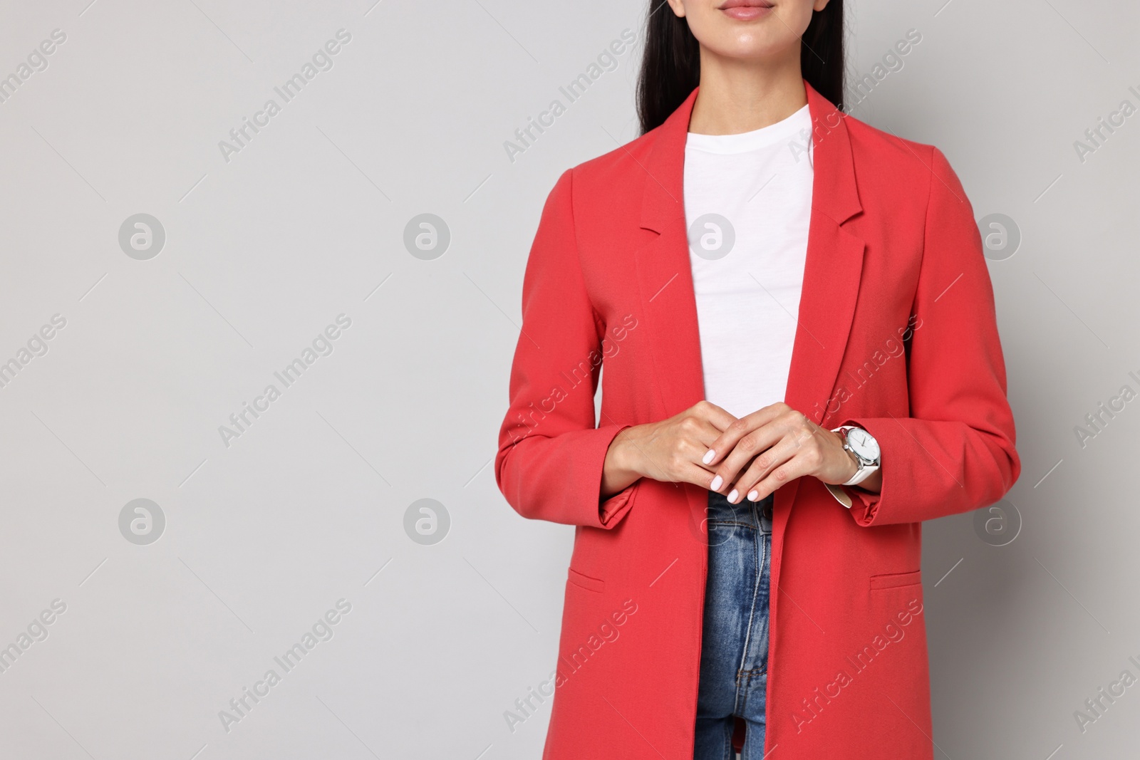 Photo of Woman in red jacket on gray background, closeup. Space for text