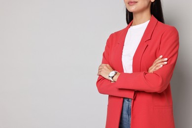 Woman in red jacket on gray background, closeup. Space for text