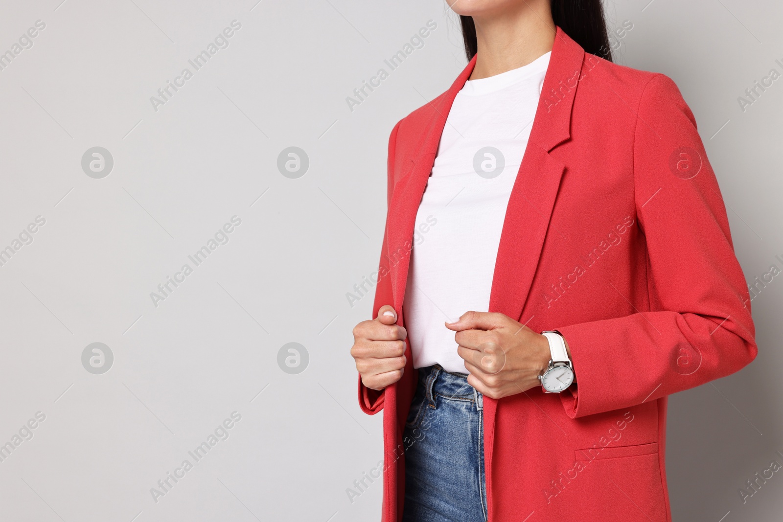 Photo of Woman in red jacket on gray background, closeup. Space for text