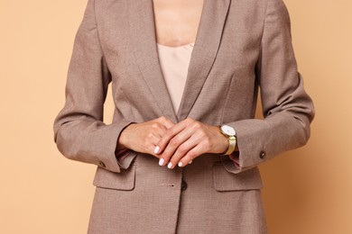 Photo of Woman in stylish jacket on pale orange background, closeup