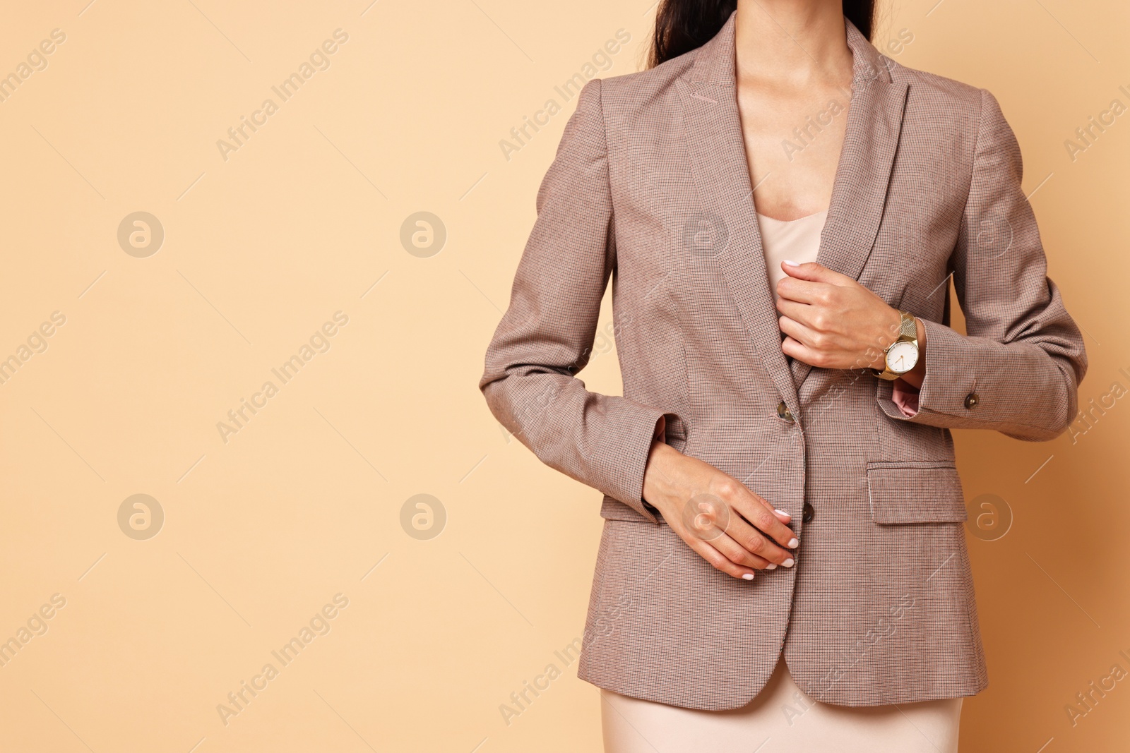 Photo of Woman in stylish jacket on pale orange background, closeup. Space for text