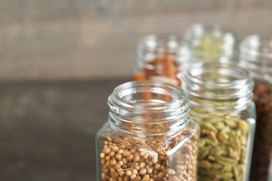 Different spices in glass jars on blurred background, closeup. Space for text