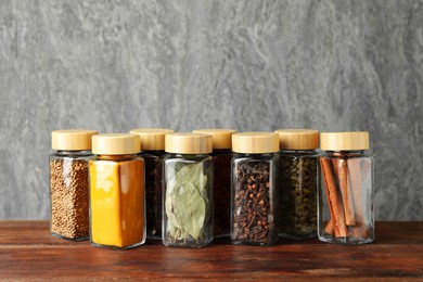 Photo of Different spices in glass jars on wooden table