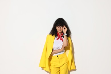 Beautiful young woman in stylish yellow suit on light background