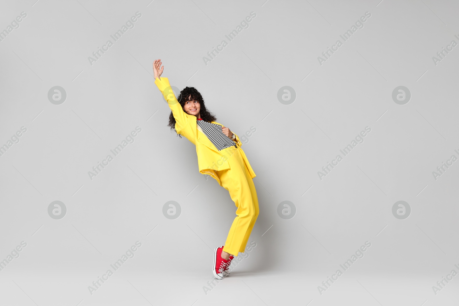 Photo of Beautiful young woman in stylish yellow suit posing on grey background