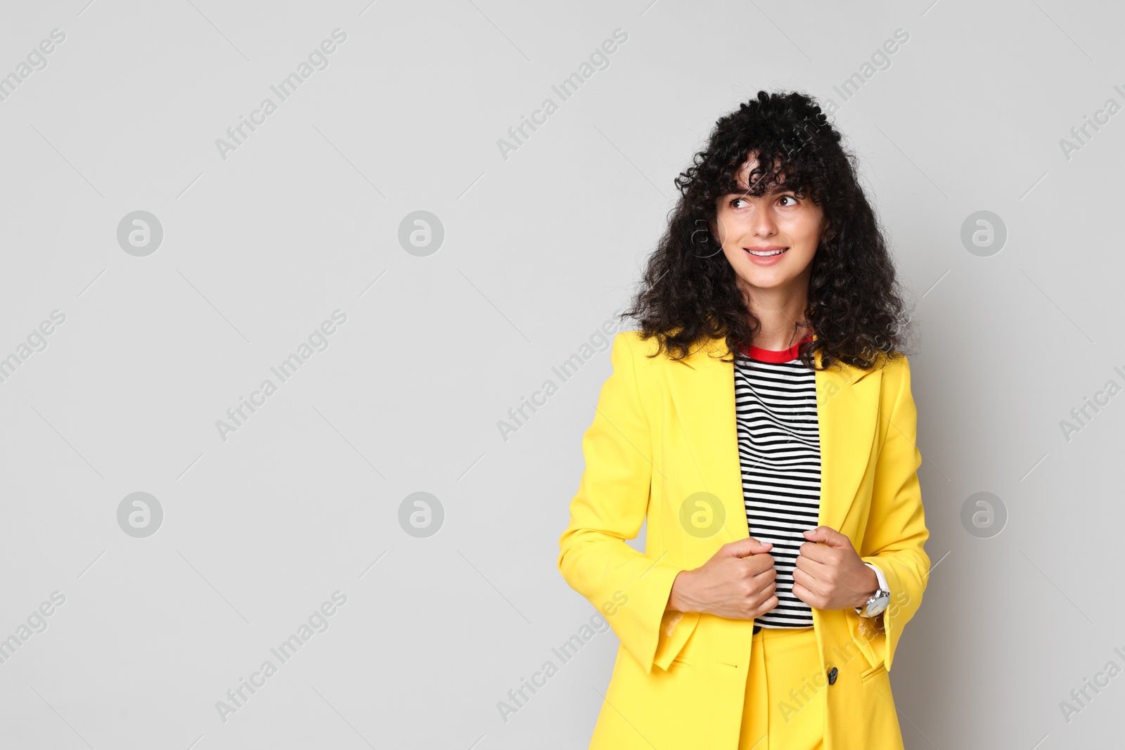 Photo of Beautiful young woman in stylish yellow suit on grey background, space for text