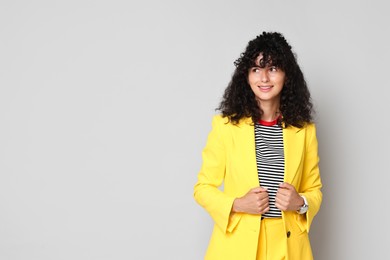 Beautiful young woman in stylish yellow suit on grey background, space for text